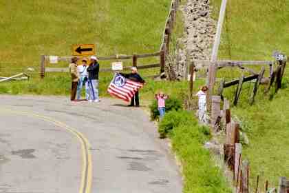 Welcoming committee at gate with peace flag.